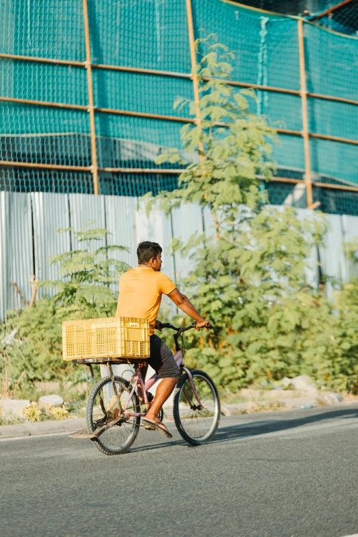 man riding a bike with lots of yellow baskets on the back