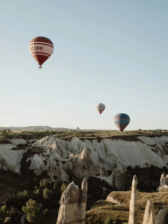 three  air balloons are flying over some rocks