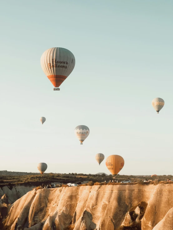 several  air balloons float through the sky above some mountains