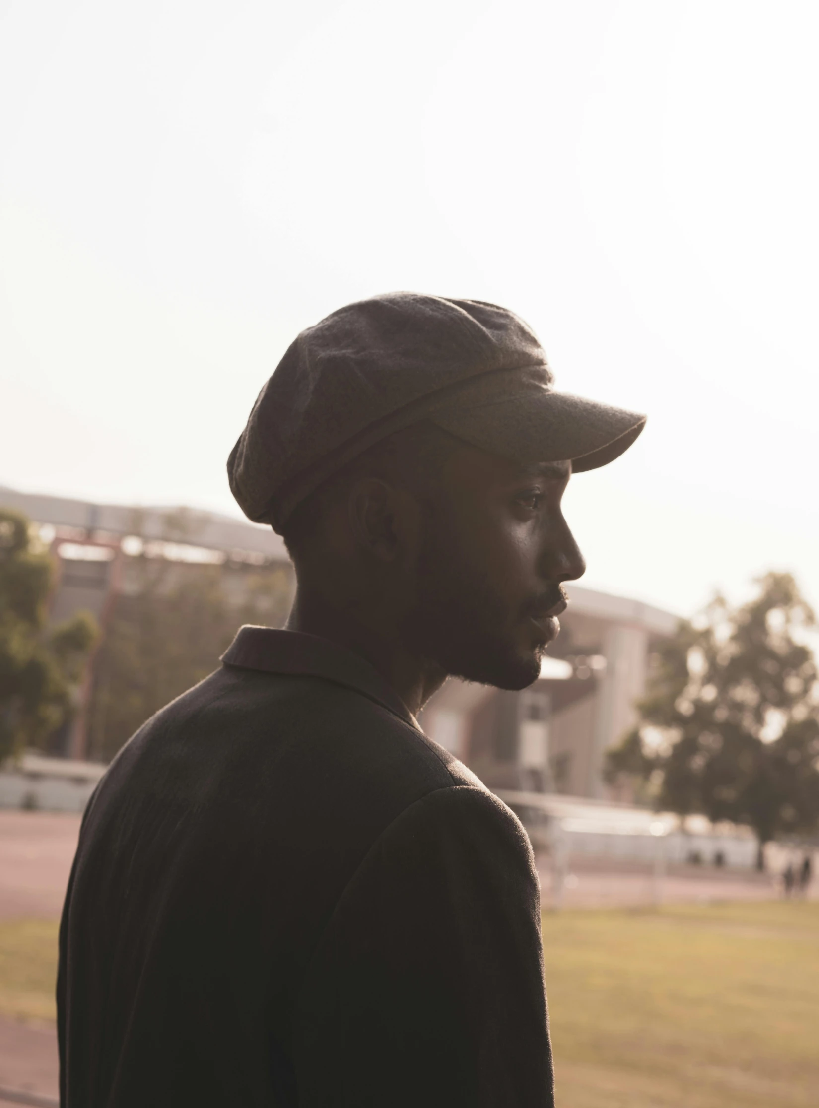 a man in a baseball cap stands next to a field