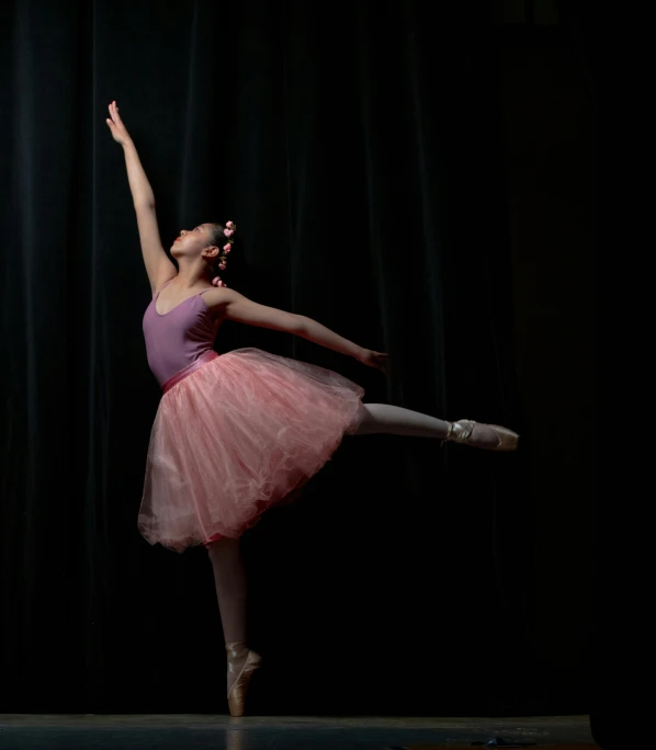 a girl in pink dress doing a ballet trick