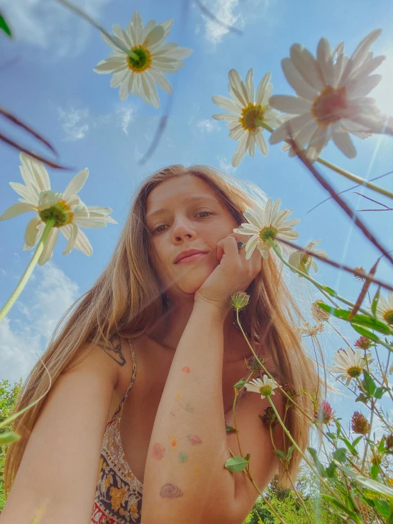 a woman stands in a field with daisies