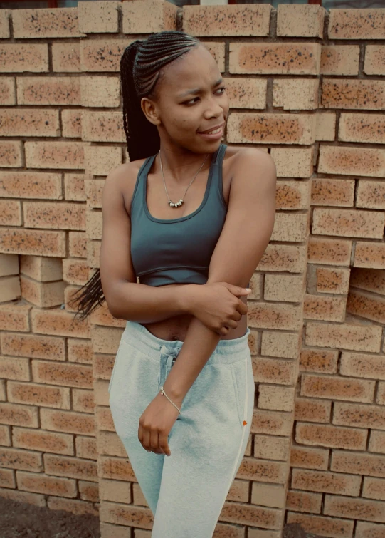 a young lady leaning against a brick wall