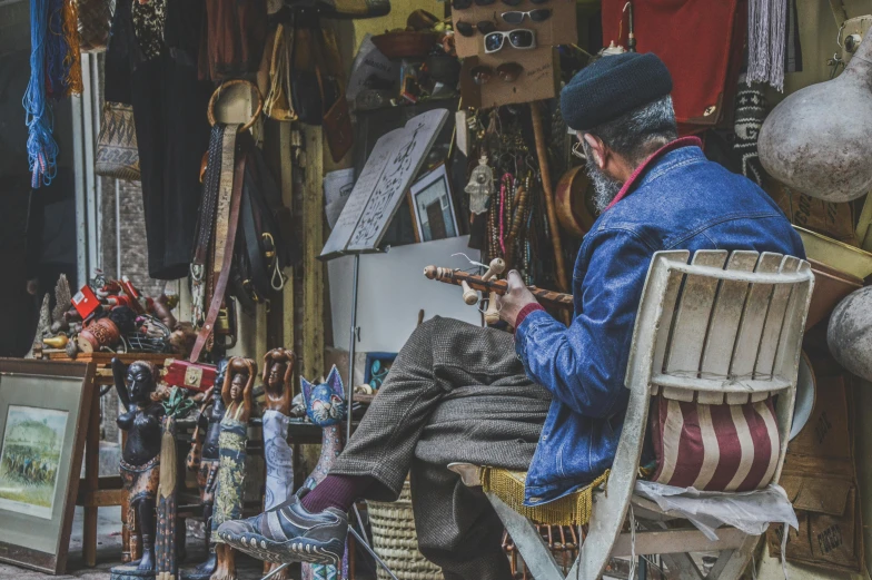 a man is sitting in an old fashioned chair while playing the violin