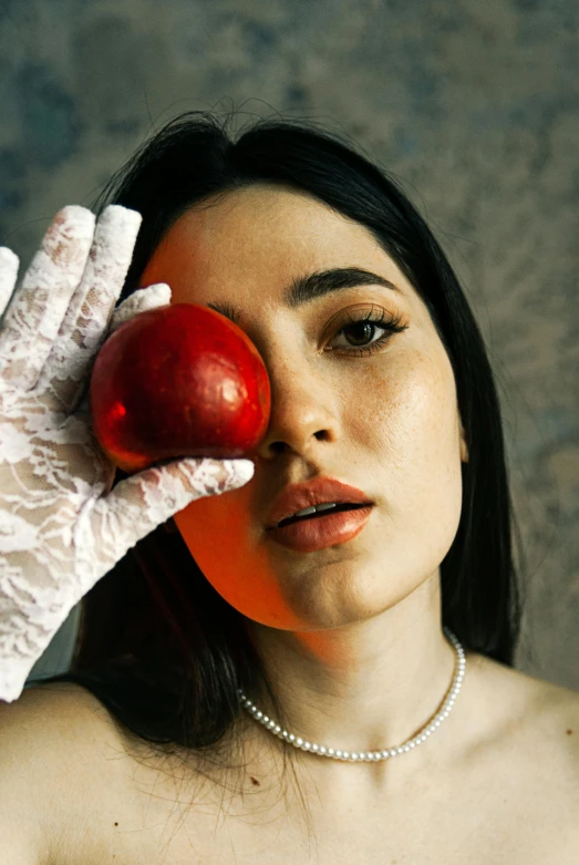 a woman holding an apple in one hand and a glove on the other