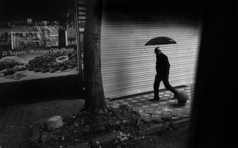 the man walks on the sidewalk with an umbrella