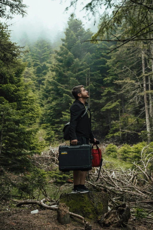 a person in the woods with a suitcase in their hand