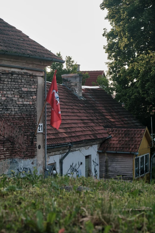 an old run down building with red roof and flag on top