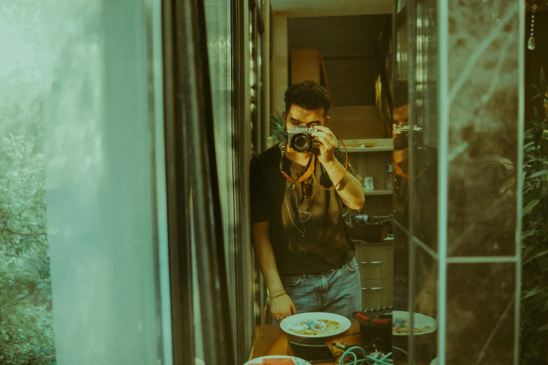 man taking po in mirror of food on table