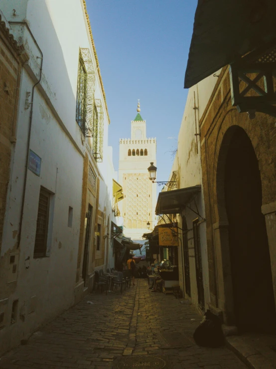 a narrow alley with a white building on the corner