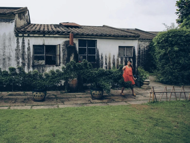 a woman in an orange dress is walking toward an old building