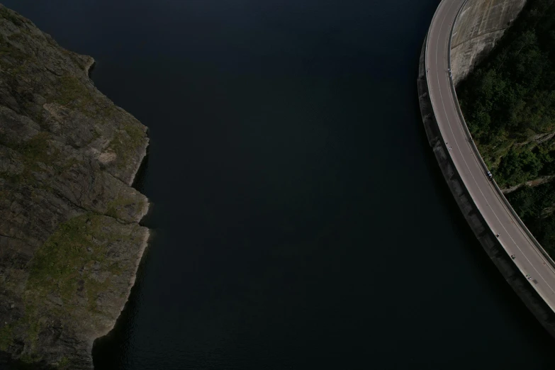 a road near the water and a bridge on one side