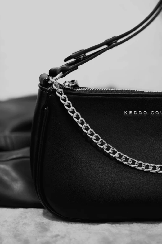 a black bag with a chain on the top and shoulder strap