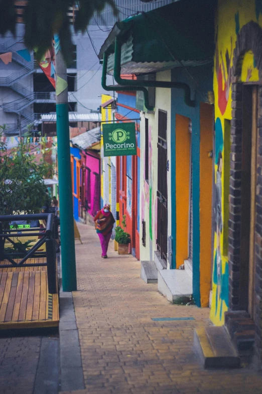 the woman walking down the street past several colorful buildings