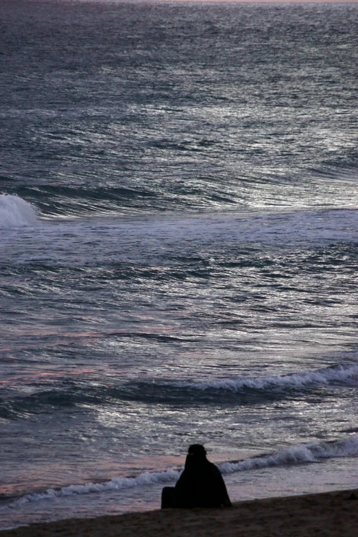 a person laying on top of a sandy beach near water