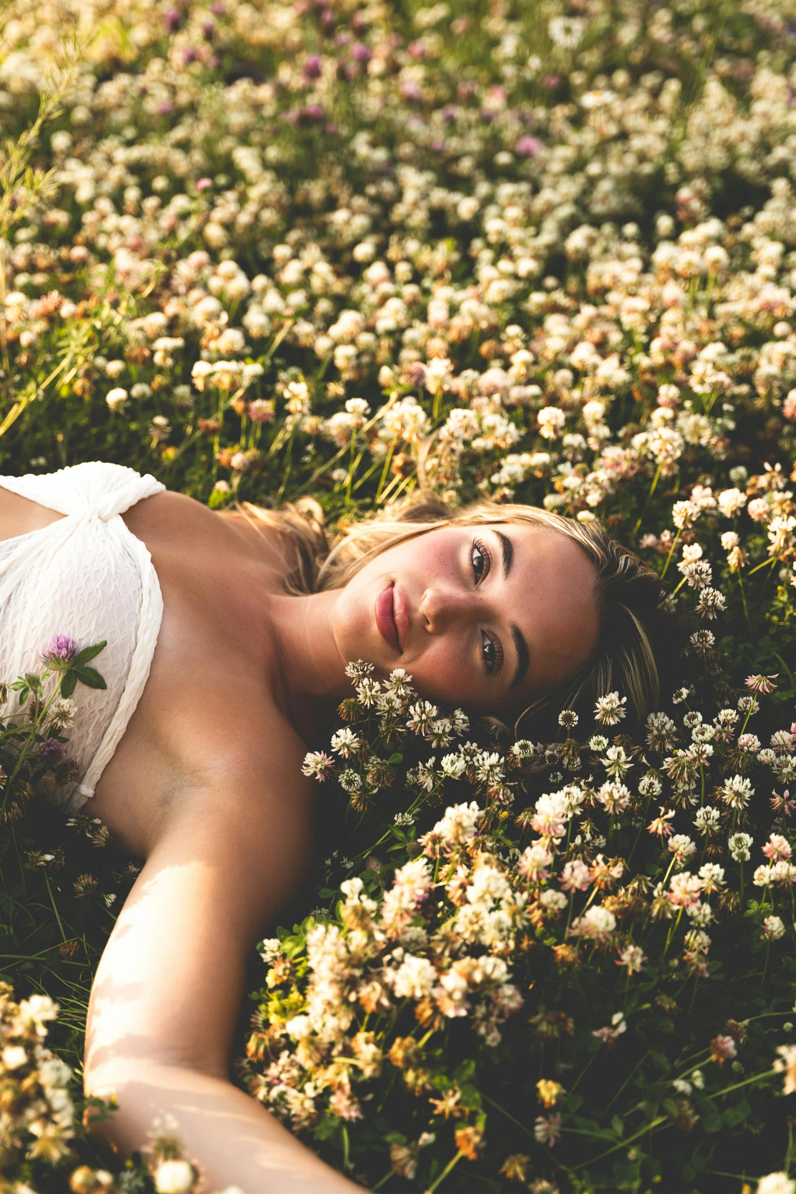 woman laying in field of flowers and looking at camera
