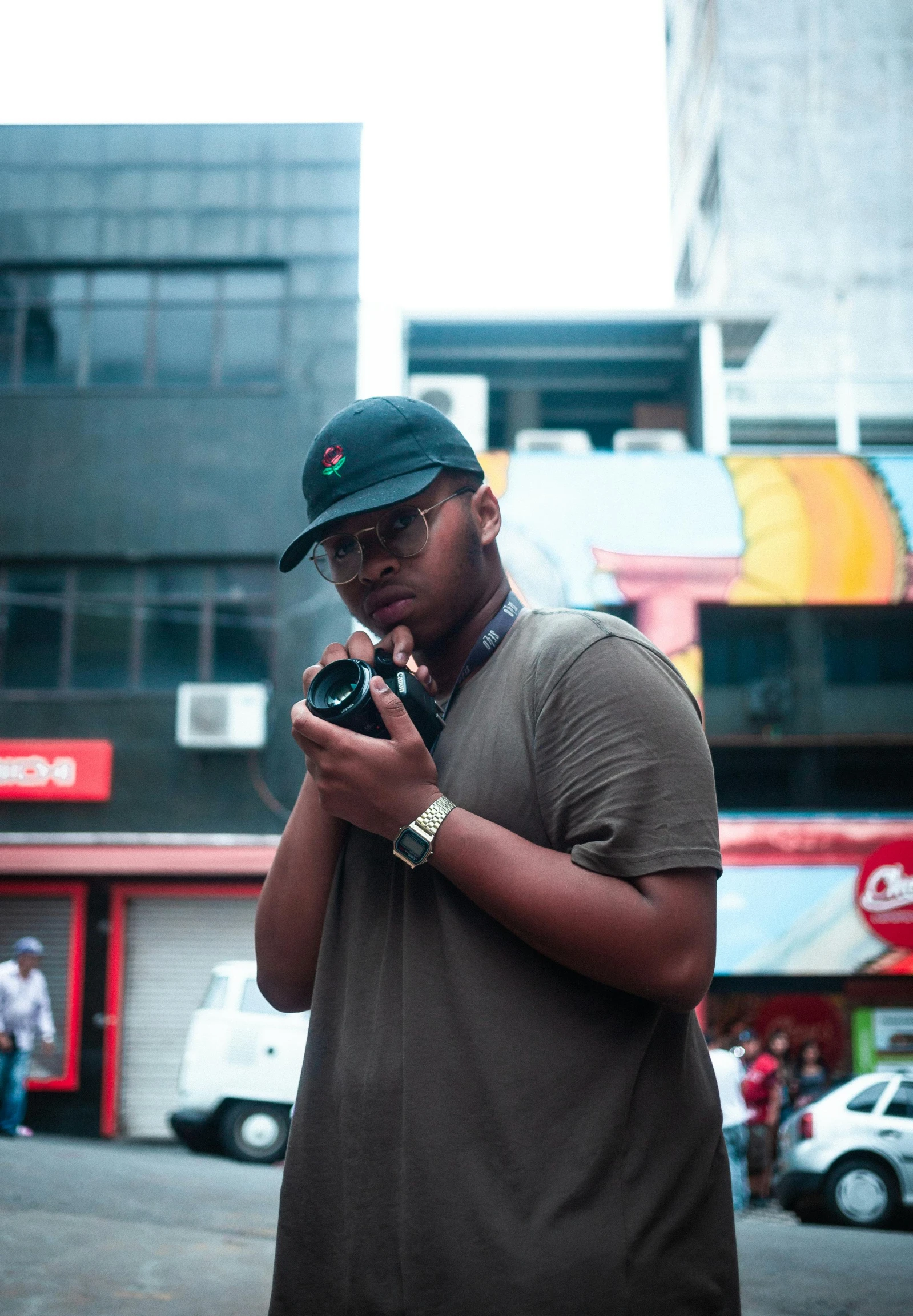 a man wearing a hat while holding a camera in his hands