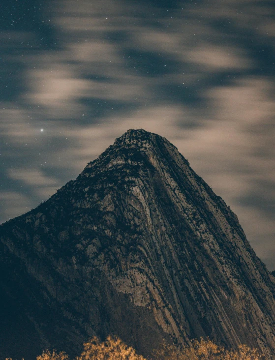 a tall mountain under the stars with trees below