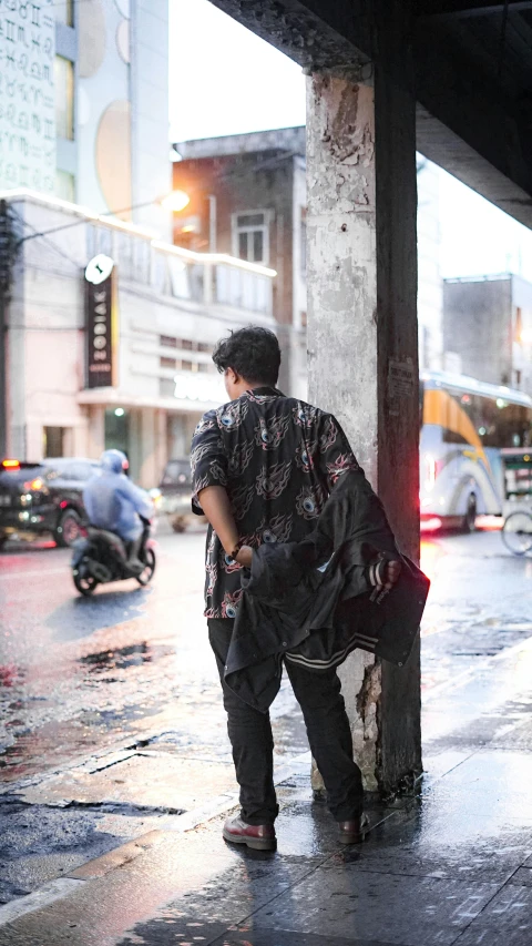 a man standing on a wet sidewalk in the rain
