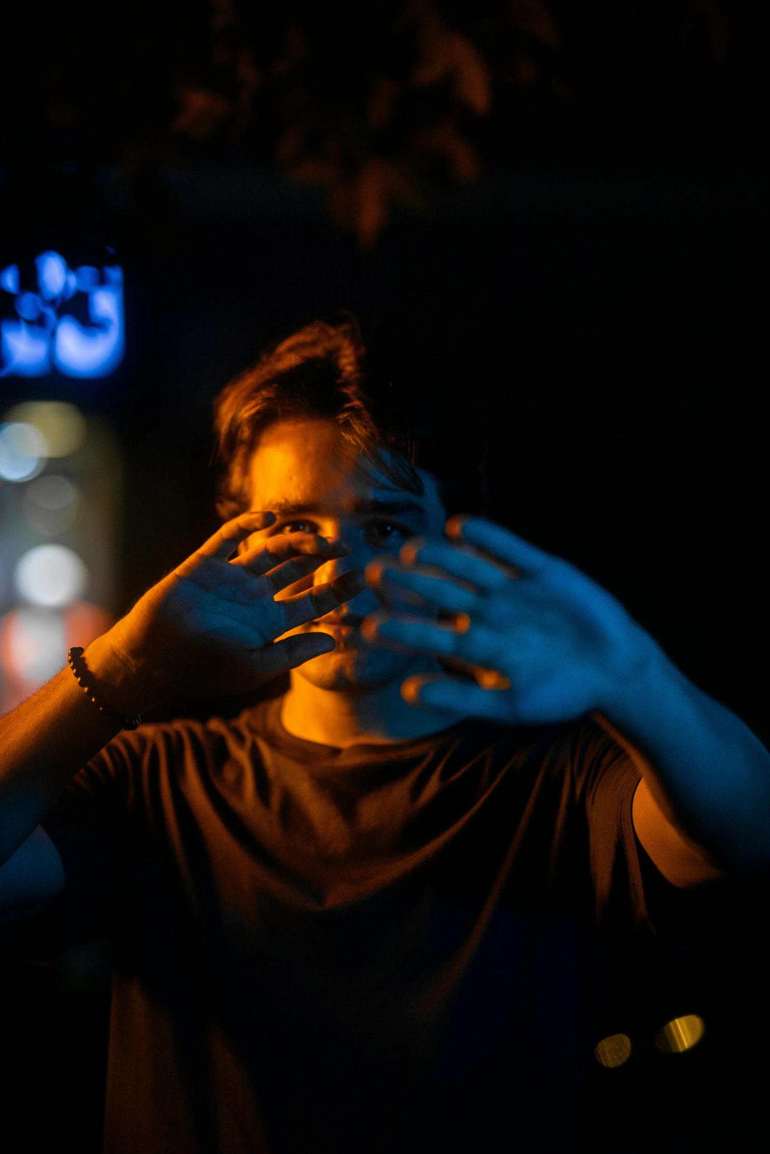 a man with long nails covering his face in the dark