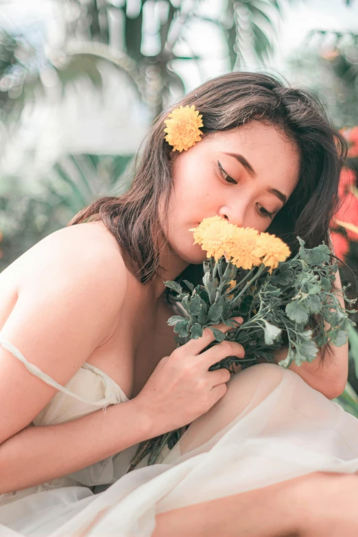 the beautiful asian girl is smelling flowers on her head