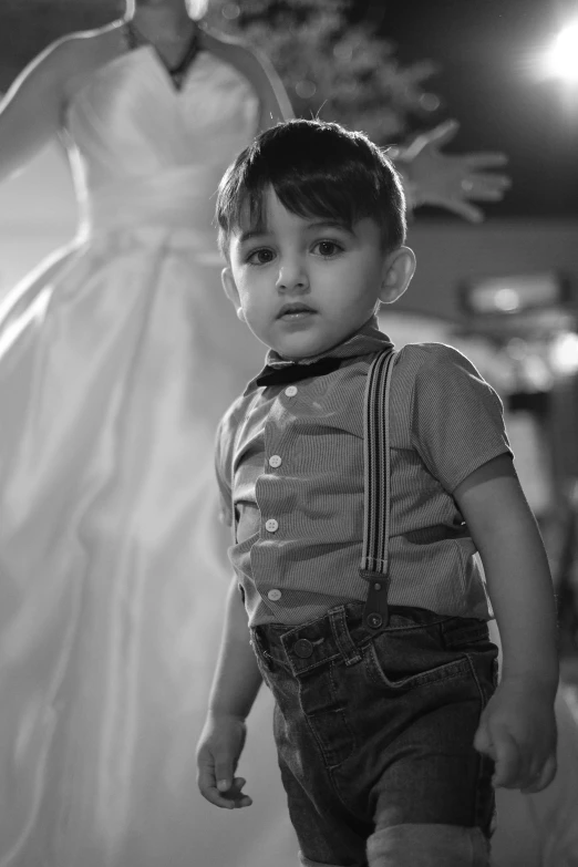 a small boy walking past a wedding gown