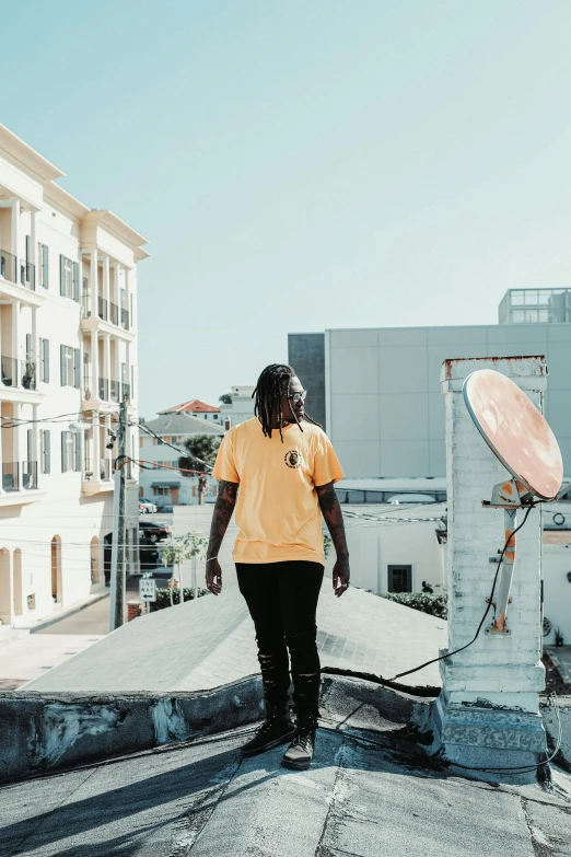 a man standing on the edge of a rooftop next to an satellite dish