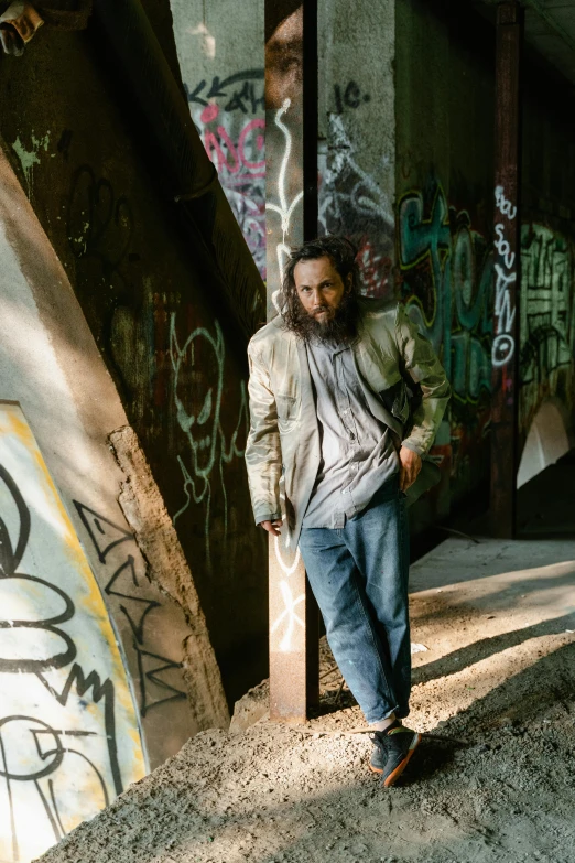 a young man stands in the alley while he holds a skateboard