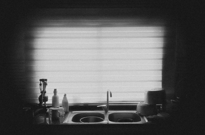 a kitchen sink under a window with lights