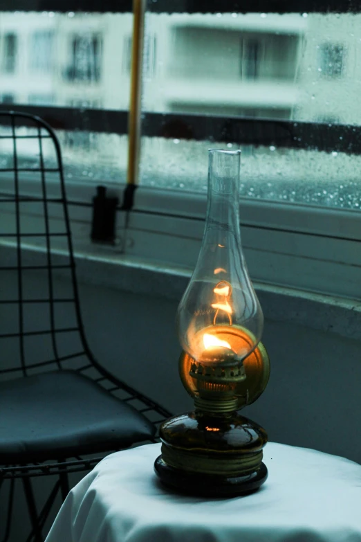 an oil lamp on a table by a window