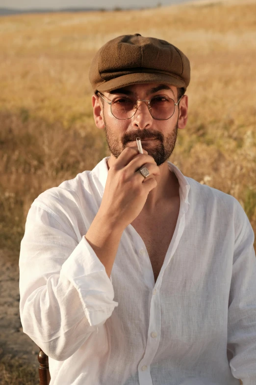 a man in white shirt and cap smoking a cigarette