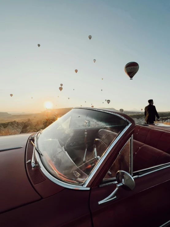 a man watching balloons flying over a car