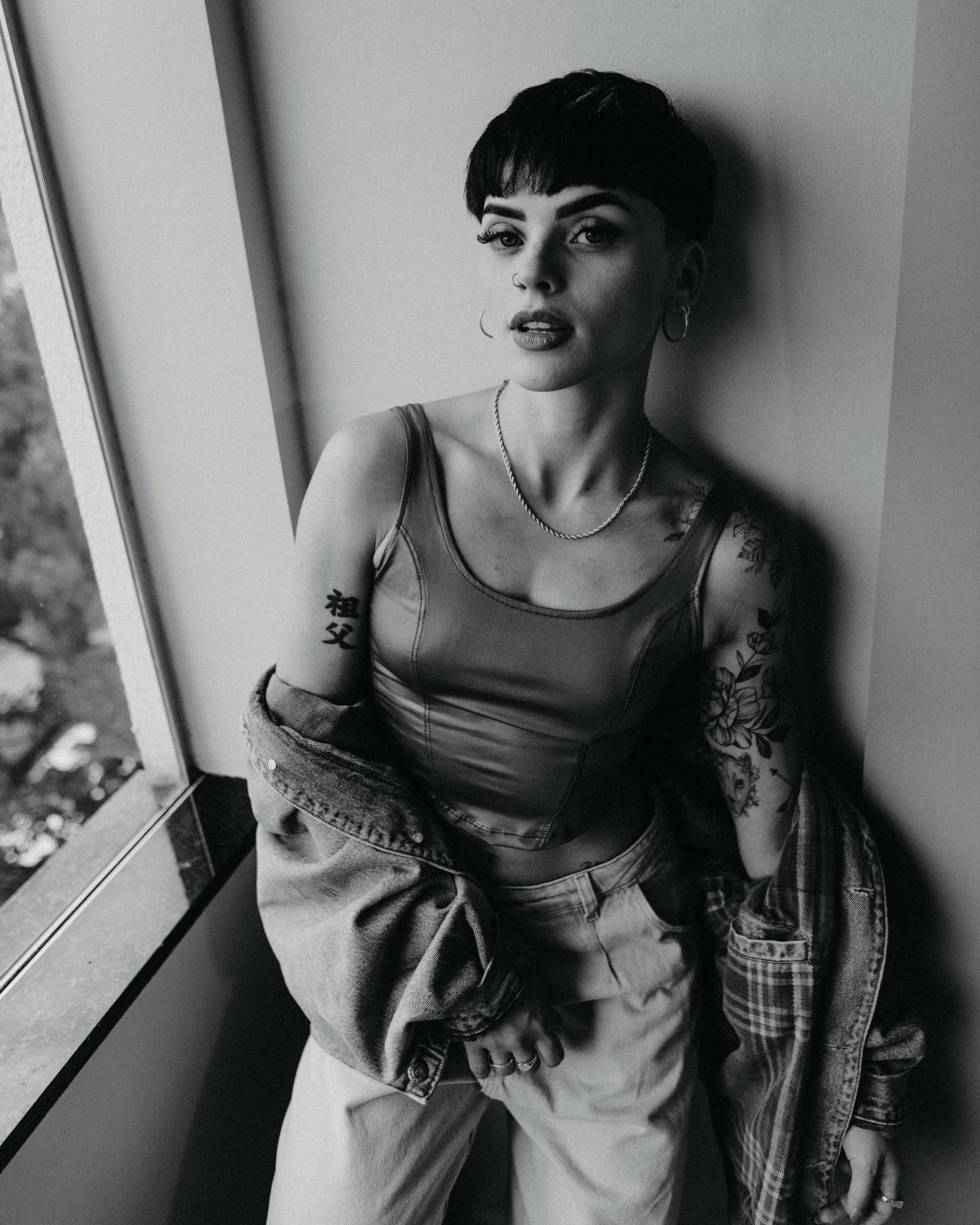 a woman leaning against a wall next to a window