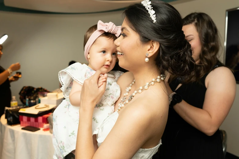 a woman holding a small child wearing a tiara