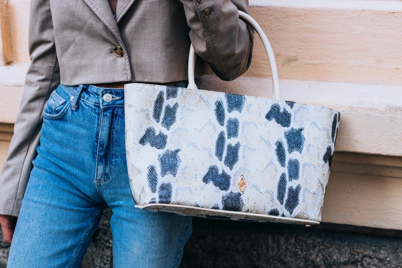 a woman in jeans and jacket holding a purse