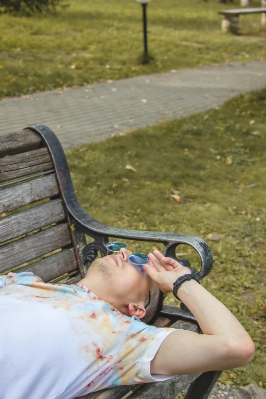 a man is asleep on a bench in the park