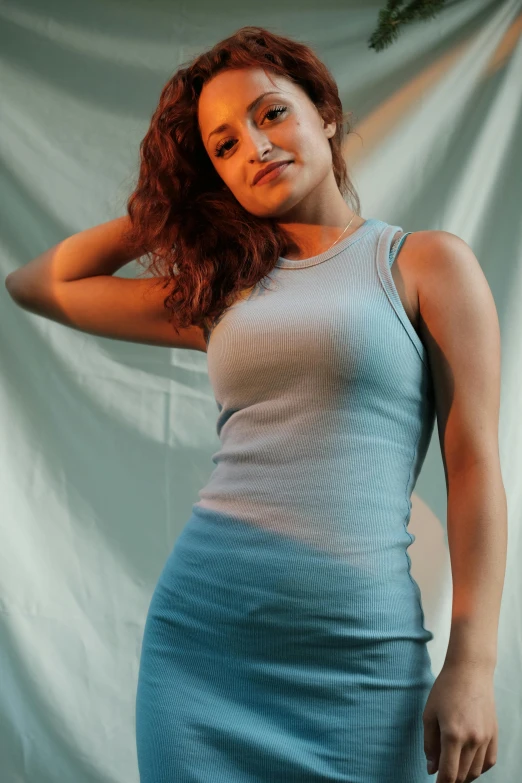 a girl poses against a backdrop wearing a light blue dress