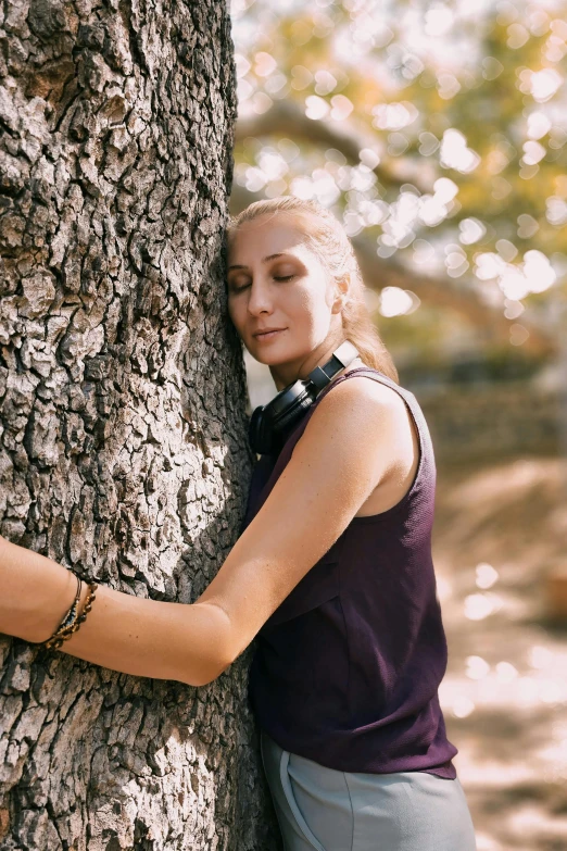 a woman leaning against a tree to hug it