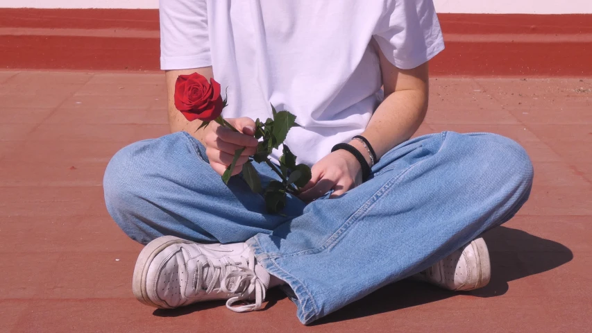 a person sitting on the floor with one flower in their hands