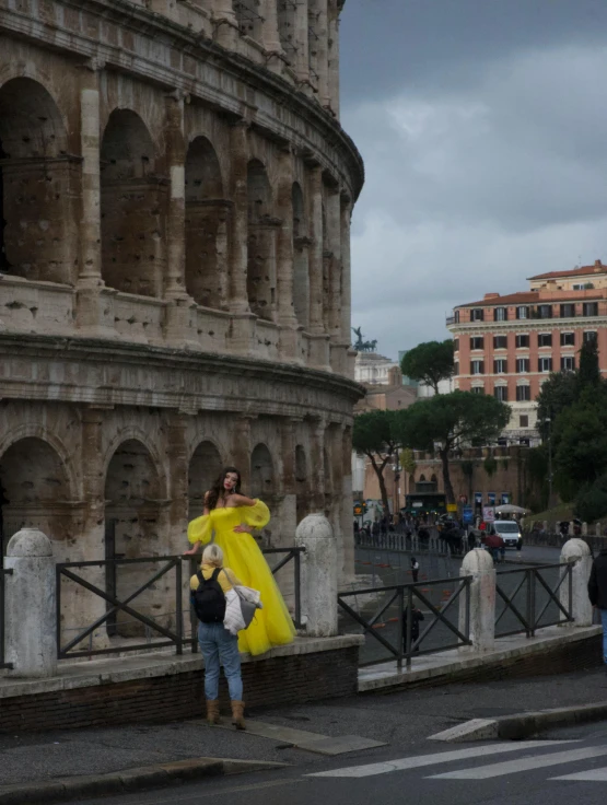 woman in yellow coat by a ancient roman structure