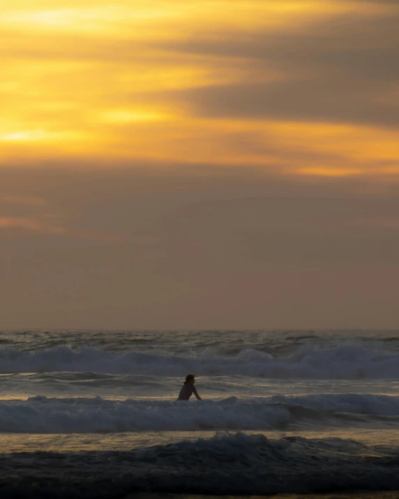 the person is surfing on the waves at sunset