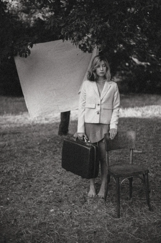 a woman holding luggage next to a tree