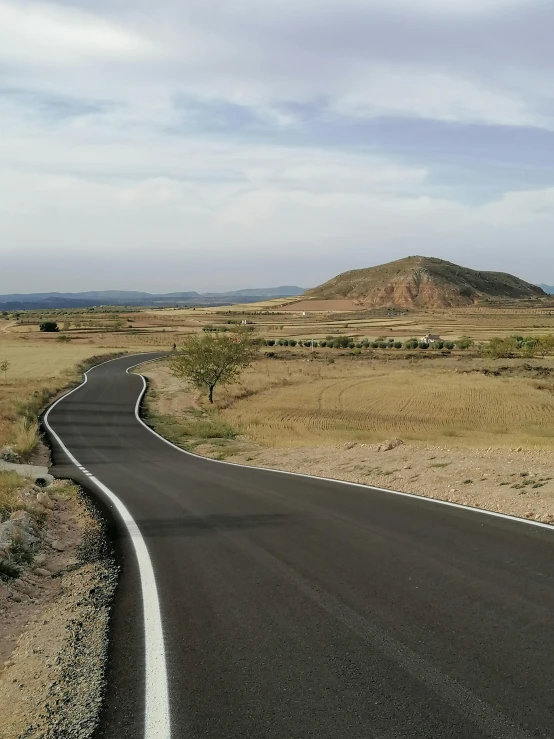 a road going down a desert plain with hills in the background