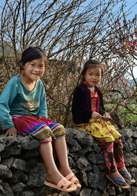 two young children sitting on rocks and smiling