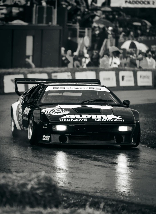 black and white pograph of an automobile racing through wet streets