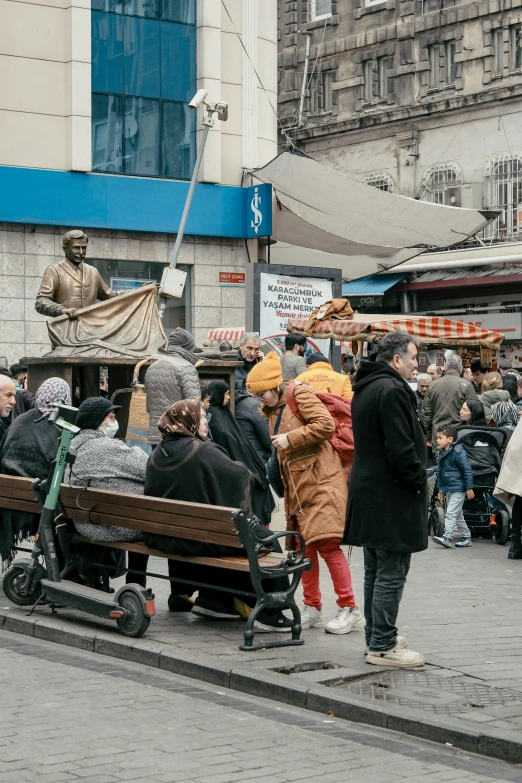 many people sitting on benches in front of some buildings