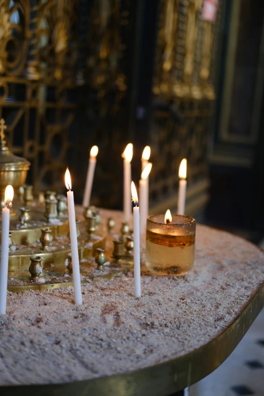 many lit candles on a table and some ss wares