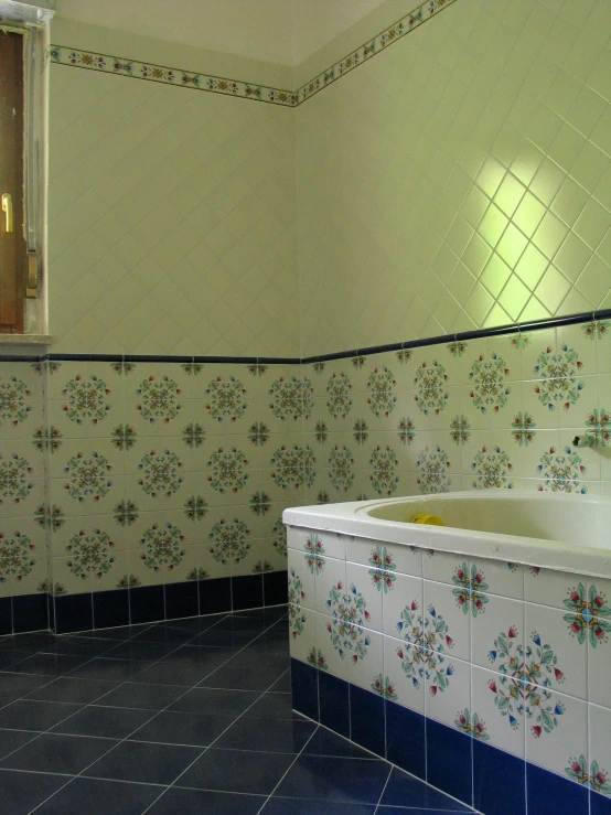 an empty bathroom with a flowered tiled tub