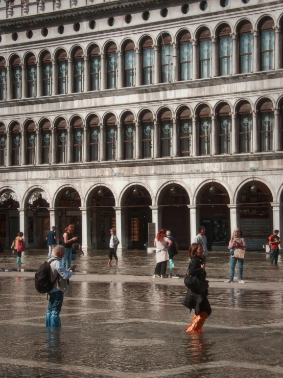 the people are walking through the courtyard with the umbrellas