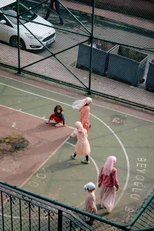 three young children in pink are playing with a basketball hoop